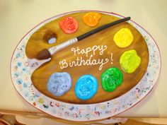 a birthday cake that has been decorated with paint and brushes on it's plate