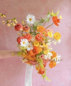 a white vase filled with lots of different colored flowers