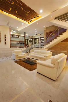 a living room filled with white furniture next to a staircase