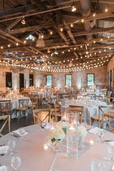 the tables are set with white flowers and lit candles for an elegant dinner or reception