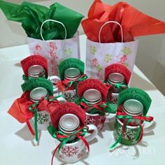 small christmas candy jars are sitting on a table with red and green paper wrapped around them