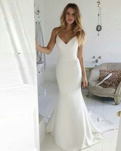 a woman in a white wedding dress standing next to a door and looking at the camera