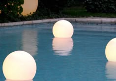 three balls are floating in the water at night