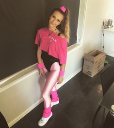 a girl in pink and black is leaning against the wall