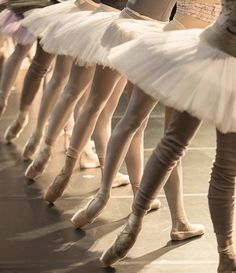 several ballerinas are lined up on the floor with their feet in the air