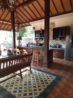 an outdoor kitchen and dining area with tile flooring on the ground, wooden tables and stools