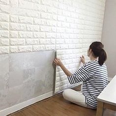 a woman is painting a brick wall with white paint