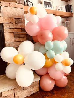 a bunch of balloons that are on top of a wooden floor in front of a fireplace