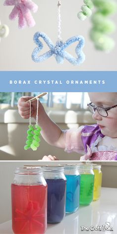 a baby is playing with colored liquid in glass jars and an ornament hanging from the ceiling