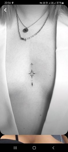 a black and white photo of a woman's chest with a cross tattoo on it