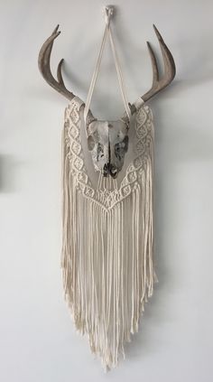 a deer skull hanging on the wall with long horns and fringes attached to it