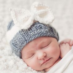 a newborn baby wearing a knitted hat with a bow