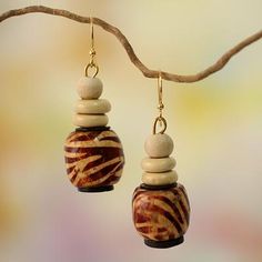 two zebra print bead earrings hanging from a tree branch with blurry back ground