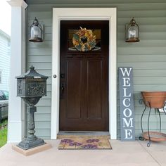 a welcome sign on the front door of a house with a mailbox and lampposts