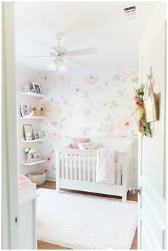 a white crib with pink flowers on the wall