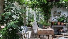 an outdoor dining area with chairs, table and potted plants