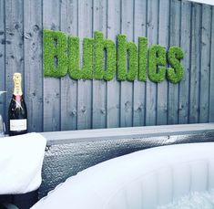 a bottle of wine sitting on top of a table next to a hot tub filled with water