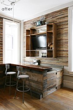 a kitchen with wooden walls and barstools in front of the counter top is an entertainment center