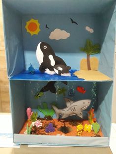 an orca whale and other sea creatures in a cardboard box with blue water inside