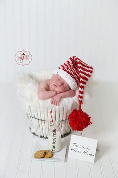 a newborn baby is sleeping in a basket with a red and white knitted hat