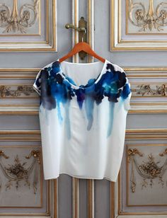 a white shirt with blue and black paint on it