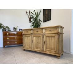 a large wooden dresser sitting next to a plant