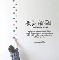 a little boy is painting on the wall with polka dot decals in black and white