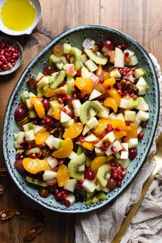 a bowl filled with fruit on top of a table next to nuts and oranges