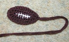 a crocheted football is laying on the ground next to a string and yarn ball