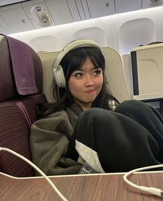 a woman wearing headphones sitting on an airplane