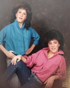 an old photo of two women sitting next to each other in front of a wall