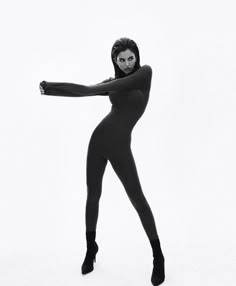 a black and white photo of a woman in full bodysuit posing with her arms stretched out