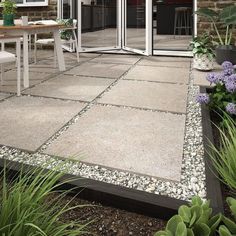 an outdoor patio area with gravel and plants on the ground, glass doors open to let in natural light