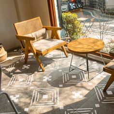 two chairs and a coffee table in front of a window with an outside patio view