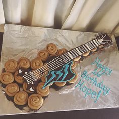 a birthday cake with an electric guitar and cupcakes in the shape of cookies