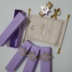 purple paper with gold decorations on it next to an envelope and other items for decoration