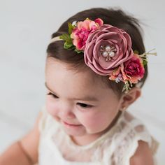 a baby girl wearing a pink flower headband