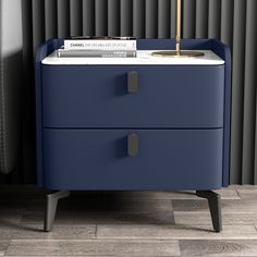 a blue nightstand with two drawers and a gold lamp on top, next to a black radiator