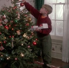 a young boy decorating a christmas tree