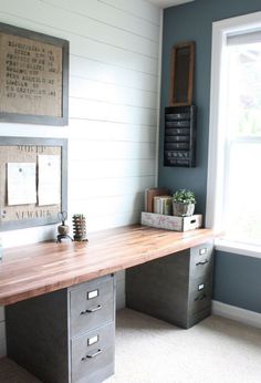 a wooden desk sitting in the middle of a room next to a window with pictures on it