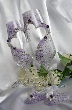 two wine glasses are sitting next to each other on a white table cloth with flowers in the background