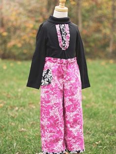 a child's pink and black outfit on a mannequin dummy in the grass