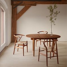 a wooden table with two chairs and a potted plant on it in front of a window