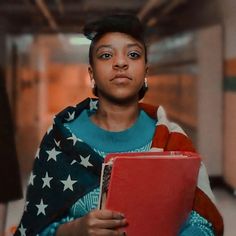 a woman holding a binder in her hand and looking off to the side with an american flag on it