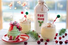 an egg nog drink is sitting on a table next to two cups with drinks in them