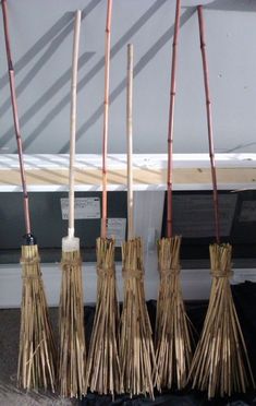 five brooms are lined up in front of a piano