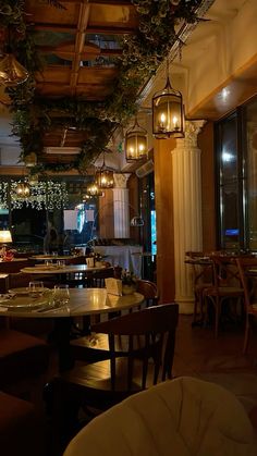 an empty restaurant with tables and chairs in front of large windows that have lights on them