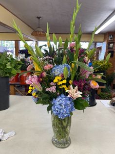 a vase filled with lots of different colored flowers on top of a white countertop