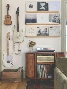 a living room filled with guitars and books on the wall above a record player's desk