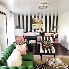 a living room with black and white stripes on the walls, green couches and zebra print rugs